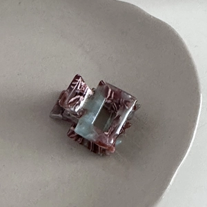 Detail shot of mini acetate square hair claw with marbled red-brown and blue texture