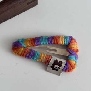 Vue détaillée d'une barrette à cheveux tricotée colorée avec étiquette d'ours mignon