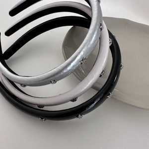 Detail view of three thick sponge headbands with silver star rhinestones in black and white