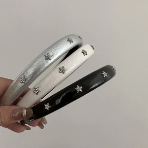 Close-up of three padded headbands in black, white, and silver with rhinestone star details