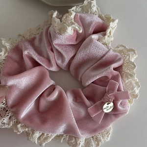 Close-up of pink velvet scrunchie with lace trim and gold charm detail