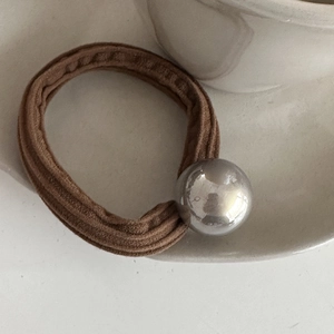 Macro shot of a dark brown elastic hair tie with a shiny silver metallic sphere bead