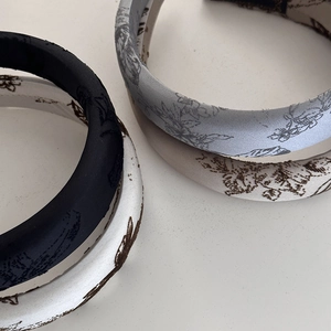 Detailed view of four satin sponge headbands featuring floral prints and solid black silk fabric
