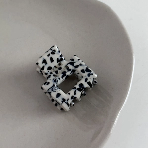 Detailed macro view of a handmade acetate mini hair claw with black and white spots