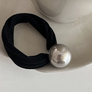 Detailed shot of elastic black hair tie featuring a polished silver metallic bead decor