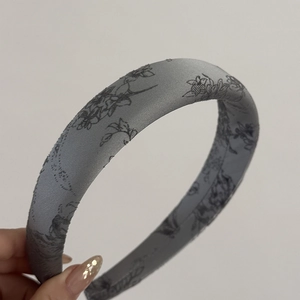 Detailed close-up of thick floral satin headband with elegant padded sponge design