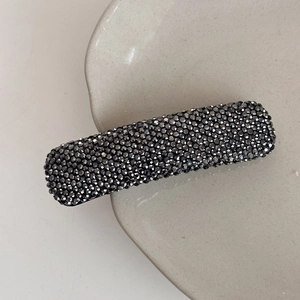 Close-up of minimalist rectangular hair clip with shimmering dark grey rhinestones