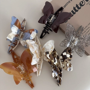Flat lay of five acetate butterfly hair claws with marble textures and metal springs