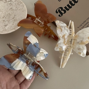 Three elegant acetate butterfly hair claws in amber, marble blue, and cream white colors