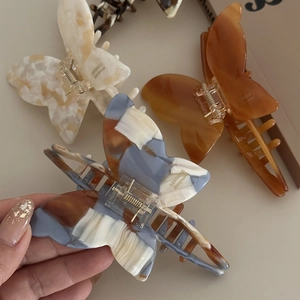 Detailed close-up of handmade butterfly acetate hair claws in various marble patterns