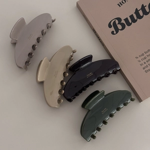 Dettaglio ravvicinato di quattro mollette in acetato nei colori grigio, beige, nero e verde