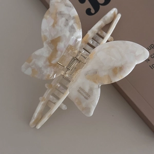 Close-up of butterfly hair claw clip with marble texture and silver metal spring detail