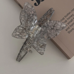 Macro shot of butterfly hair claw clip with grey marble pattern and metal spring