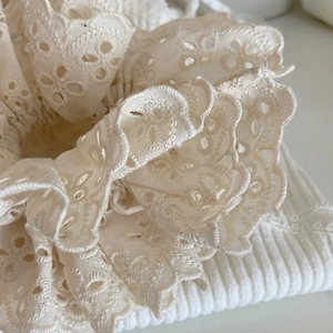 Detalle de los volantes de encaje crema y bordados en un coletero de calidad