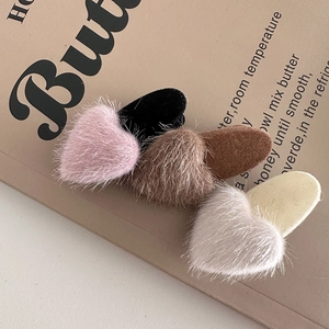 Detail showing four colors of plush heart-shaped hair clips in pink, black, brown and beige