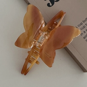 Detail of amber acetate butterfly hair claw with marble texture on an old book