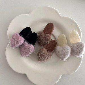 Detailed view of plush heart hair clips in pink, coffee, and beige on a white ceramic plate