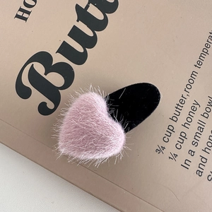 Detail of pink faux fur heart hair clip with black velvet base on vintage paper