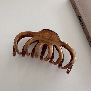 Grosse pince à cheveux en résine ambre avec texture écaille de tortue sur fond en cuir beige