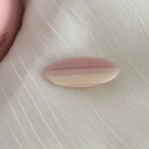 Détail de la barrette dégradé rose et crème sur un tissu beige texturé