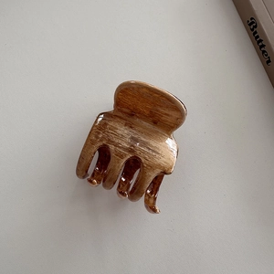 Gros plan détaillé sur une pince à cheveux marron texture bois sur fond gris minimaliste
