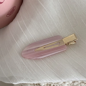 Détail de la pince à cheveux en acétate rose marbré avec base en métal doré et forme de goutte
