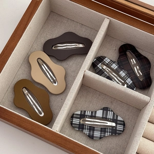 Close-up of five-piece set plaid and solid wave-shaped BB hair clips in a wooden tray