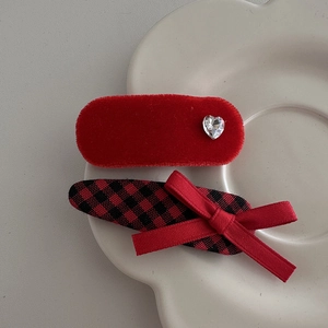 Detail of red velvet and plaid hair clips with crystal heart on white ceramic tray
