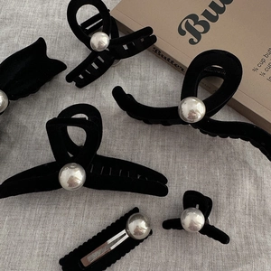 Elegant black velvet hair claw set with silver pearl spheres on a textured grey fabric