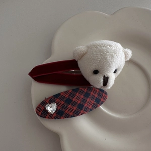 Detail of red plush hair clips with cute white bear and heart rhinestone on a ceramic tray