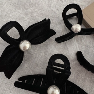 Elegant black flocked hair claw clips with large pearls set on natural linen fabric