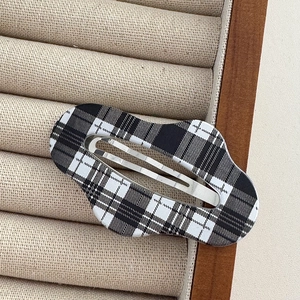 Detail of checkered cloud-shaped hair clip on a beige velvet jewelry display tray
