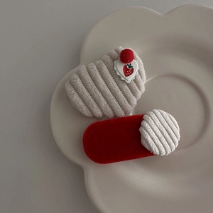 Close-up of beige corduroy strawberry hair clip and red velvet barrette set on white tray