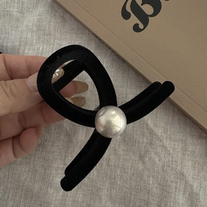 Detail shot of black flocked hair claw clip featuring a large silver faux pearl accent