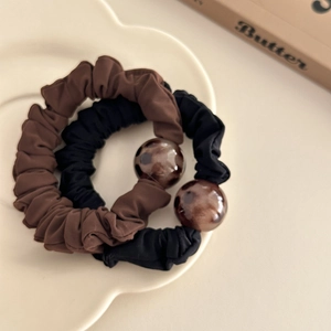 Brown leopard print scrunchies with acrylic ball charms in a white decorative tray