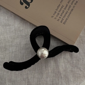 Close-up of a large black velvet hair claw clip with a silver bead on a linen texture