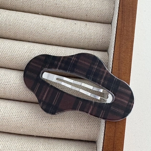 Detailed close-up of brown checkered acetate hair clip with silver metal snap back