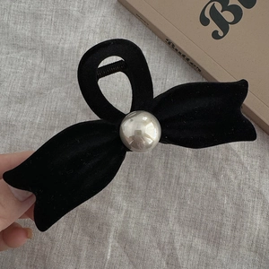 Detailed view of black velvet bow hair claw clip with silver bead on textured fabric