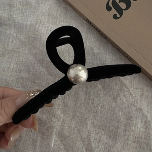 Detail of elegant black flocked hair claw clip with a large pearl decoration