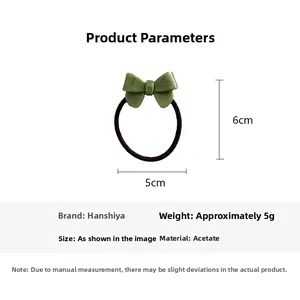 Detail showing acetate green bow hair tie dimensions 5x6cm with gold label lettering