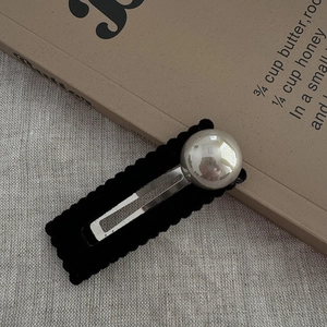 Detail of black flocked shark clip with large silver sphere on vintage book background