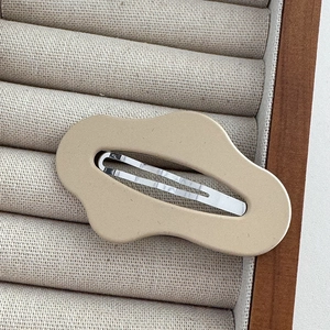 Close-up of matte cream cloud-shaped BB hair clip on beige velvet display stand