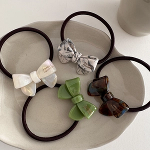 Set of premium acetate bow hair ties in pearl white and marble textures on ceramic tray
