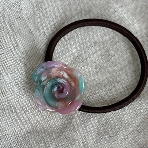 Dettaglio dell'elastico rosa in resina a forma di rosa su tessuto di lino neutro