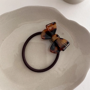 Close-up of tortoiseshell acetate bow hair tie with France Handmade gold lettering