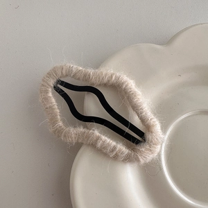 Detail view of plush beige faux fur hair clip with metal BB grip on ceramic petal plate