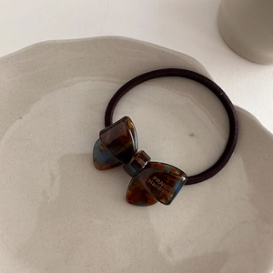 Detail view of acetate tortoise shell bow hair tie with France Handmade gold lettering