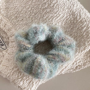Macro detail of plaid fuzzy scrunchie on warm knit sweater showing soft texture