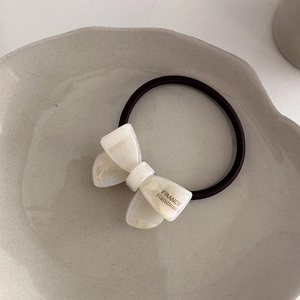 Macro shot of high-elasticity hair tie with a cream acetate bow and gold lettering