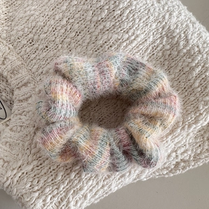 Close-up of soft colorful plush scrunchie with fluffy texture on white knit fabric